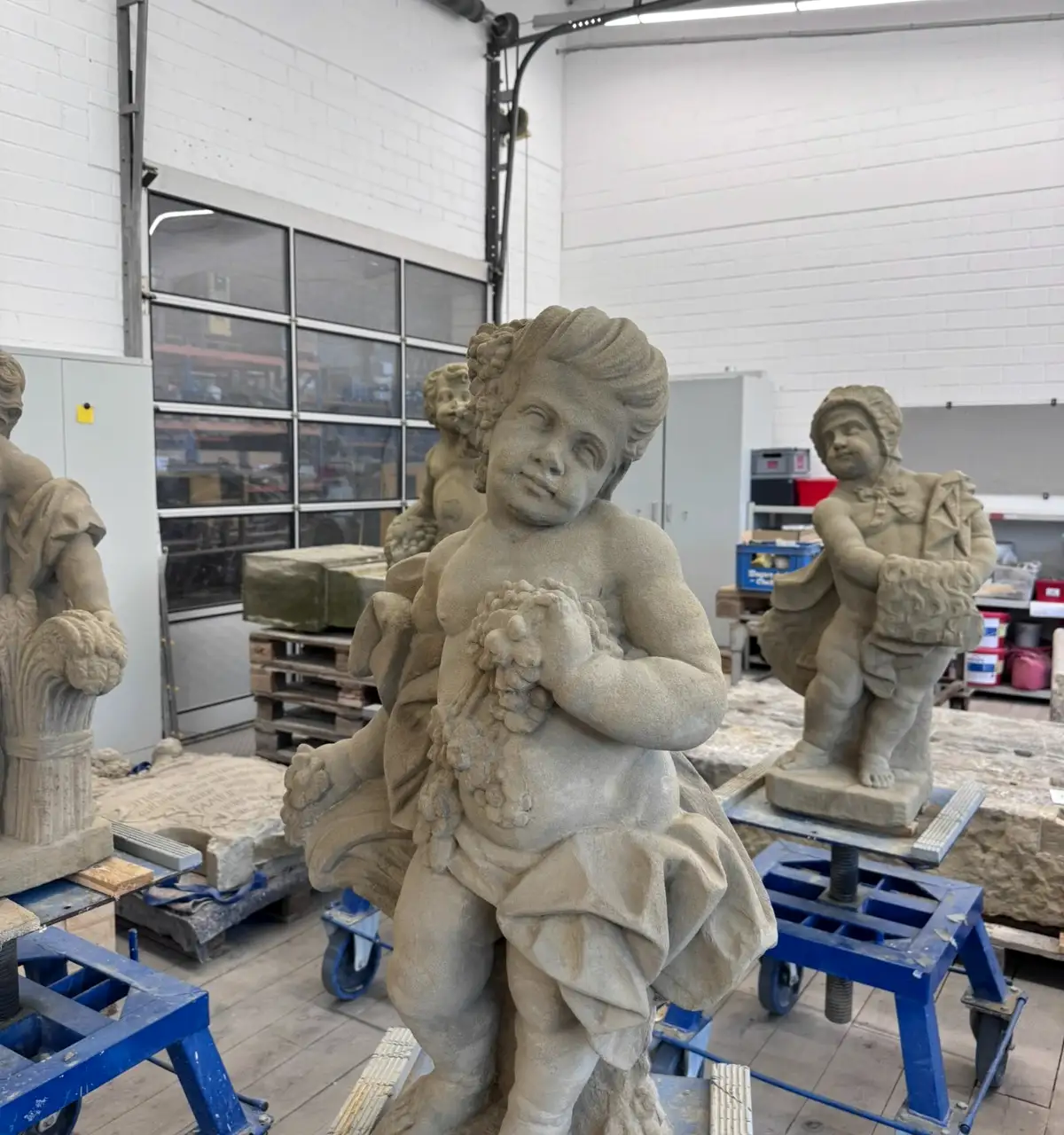 Sandsteinfiguren auf Paletten in einer Restaurierungswerkstatt