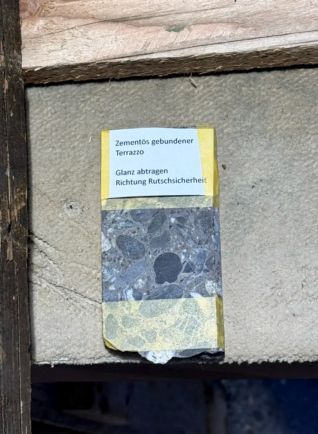 Abgeklebte Probe auf einer Terrazzoplatte mit aufgeklebtem Bearbeitungsetikett